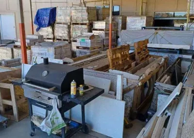 A cluttered warehouse with various construction materials and a barbecue grill